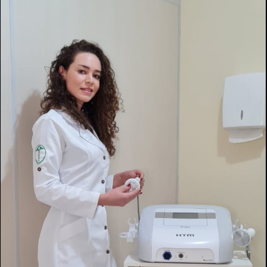Esteticista da Ana Maria Estética Avançada com aparelho de tratamento facial na sala de atendimento